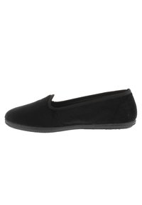 Scarpa nera slip-on realizzata in tessuto morbido con suola in gomma piatta, punta arrotondata e design minimalista, caratterizzata da una texture liscia e priva di motivi.