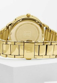 Gold Edelstahl-Armbanduhr mit polierter Oberfläche, runder Gehäuseform, Krone und Gliederarmband. Gravierter Boden.