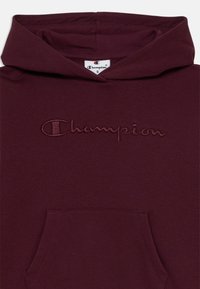 Haut à capuche bourgogne avec cordon de serrage, poche kangourou et logo "Champion" brodé sur la poitrine dans un fil assorti.