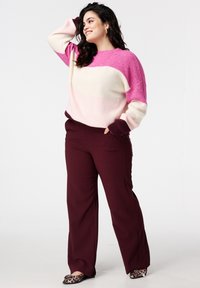 Gebreide trui in roze en crèmekleurige gradient met lange mouwen; gecombineerd met bordeauxrode broek met wijde pijpen en dierenprint ballerina's.