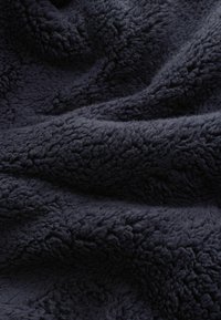 Mørk navy tekstureret fleece-stof med et blødt, luksuriøst udseende, der har en tæt og plyssy overflade, som skaber et varmt og indbydende look.