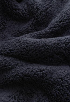 Ciemnonavy materiał polarowy o teksturze, z miękkim i puszystym wyglądem, charakteryzujący się gęstą i puszystą powierzchnią, która tworzy ciepły i przytulny wygląd.