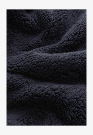 Mørk navy tekstureret fleece-stof med et blødt, luksuriøst udseende, der har en tæt og plyssy overflade, som skaber et varmt og indbydende look.