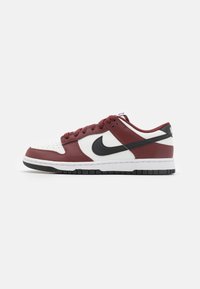 Sneakers Nike Dunk Low con una tomaia in pelle bordeaux e bianca, Swoosh nero, punta rotonda e suola spessa bianca con accenti neri.