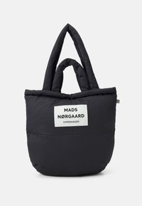 Zwarte, fluffy totebag met dubbele handvatten, voorzien van een wit label met de tekst "MADS NØRGAARD COPENHAGEN." Zachte textuur en ronde vorm.