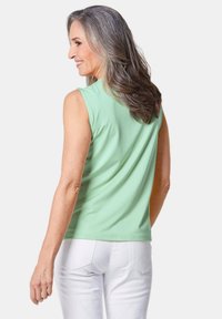 Mouwloze mintgroene top van zachte stof, met een ontspannen pasvorm en een ronde halslijn, gecombineerd met witte denim broek.