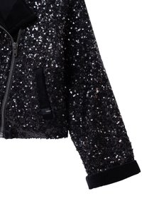 Czarna bomberka z cekinami, z zapięciem na zamek błyskawiczny, welurowym kołnierzem i mankietami. Posiada boczną kieszeń oraz małą metkę marki na kieszeni.