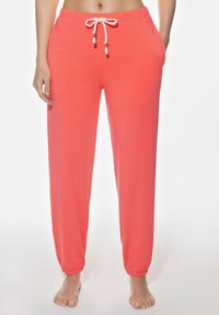 Korallfärgade joggerbyxor med elastisk midja, justerbar dragsko, sidofickor och elastiska fållar vid anklarna. Slät textur.