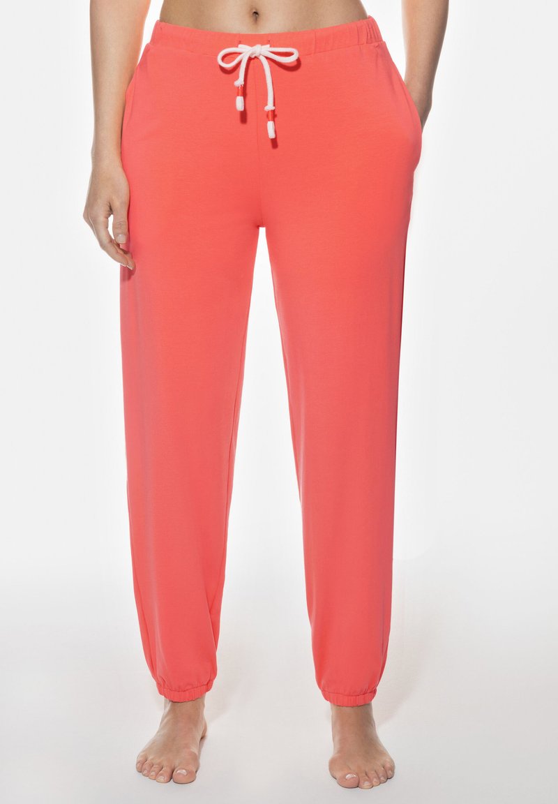 Korallfärgade joggerbyxor med elastisk midja, justerbar dragsko, sidofickor och elastiska fållar vid anklarna. Slät textur.