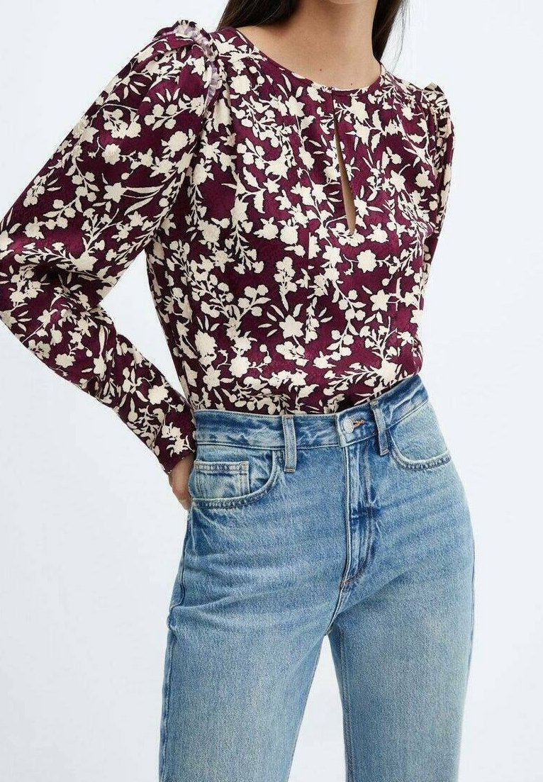 Haut à manches longues bordeaux à motifs floraux avec un détail d'encolure en trou de serrure, associé à un jean bleu clair taille haute. Le tissu présente une texture à motifs.