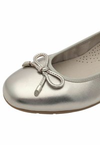 Metallisch silberne Ballerina mit weicher Textur, runder Zehenpartie und einer Schleifenakzentuierung. Verfügt über ein gepolstertes Innenleben und eine flexible Sohle.