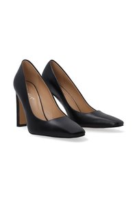 Black leather high-heeled pumps with pointed toes, smooth finish, and chunky heels. Interior is beige with subtle branding detail.