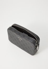 Bolsa de cremallera de color gris con patrón, hecha de material texturizado, que presenta un acento metálico de marca y un forro suave. Forma rectangular compacta.