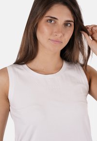 Top bianco senza maniche realizzato in materiale morbido, con colletto a girocollo e discreta branding "YES·ZEE" sul davanti. Texture liscia.