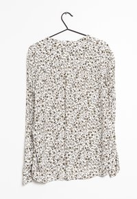 Blusa a maniche lunghe con uno sfondo bianco e un motivo floreale marrone. Presenta un collo rotondo e un design ampio e fluido.