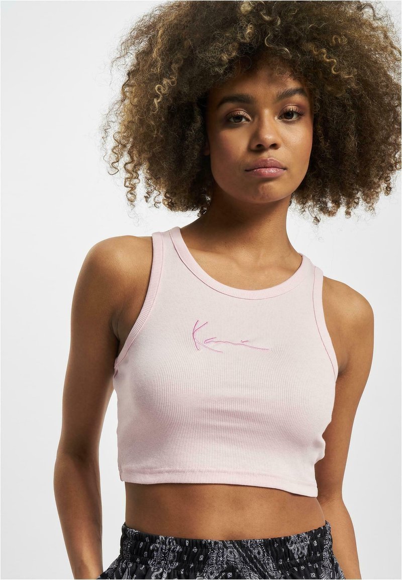 Rosa ribbet cropped tank top med rund hals og rosa brodert signaturdetalj foran. Myk, elastisk stoff.