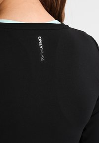 Schwarzes Sportshirt mit Rundhalsausschnitt, glatter Textur, mit dem "ONLY PLAY" Logo in Weiß auf dem Rücken, akzentuiert durch Hellblau darunter.