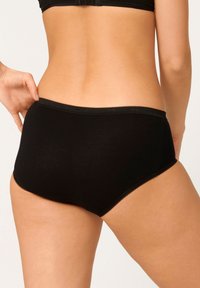 Mutande alte in cotone nero con una texture liscia, caratterizzate da un bordo ondulato. Il design enfatizza il comfort e la copertura.