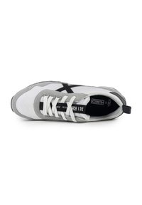 Zapatilla que presenta una parte superior de malla blanca con acentos de ante gris, logotipo negro, cordones blancos planos y una suela de goma texturizada.