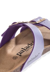 Lila lädersandal med en texturerad fotbädd, med överlappande remmar och en guldfärgad spänne. Lätt korksula, märkt "palado."