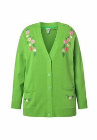 Grön stickad kofta med V-ringning, knappstängning, två framfickor och blommönster i rosa och vitt på axlarna.