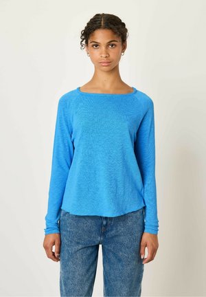Long-sleeve, crew-neck top in bright blue, made of textured fabric. Features a relaxed fit and a slightly cropped hem. Worn with denim jeans.