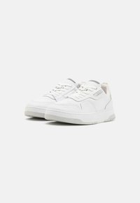 Sneakers bianchi con tomaia in pelle testurizzata, punta rotonda e suola in gomma spessa. Presentano lacci e un piccolo dettaglio in argento vicino al tallone.