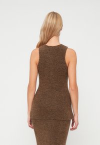 Brązowy bezrękawnik dzianinowy o teksturowanym wykończeniu, charakteryzujący się dopasowanym krojem i okrągłym dekoltem, prezentujący gładki tył.