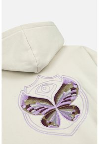 Crème hoodie met een groot geborduurd vlinderontwerp in paarse en bruine tinten, omlijnd met een lichtpaarse rand.