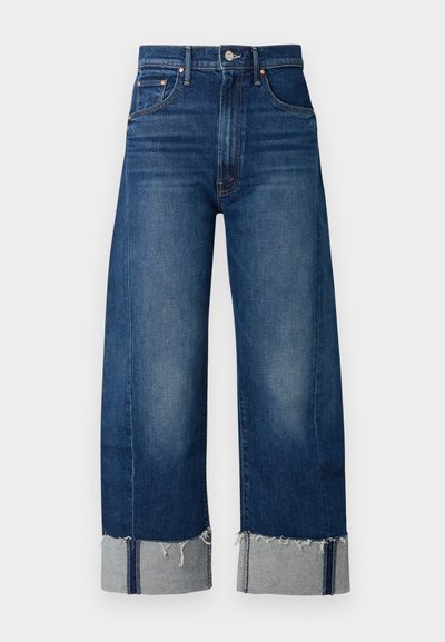 Temno modri široki kavbojski hlače iz denima z raztrganim robom in svetlo sivimi manšetami. Imajo tradicionalen dizajn s petimi žepi.