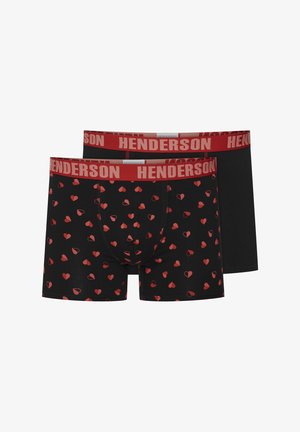 Zwei Paare Männerboxershorts; eine mit schwarzem Hintergrund und rotem Herzmuster, die andere einfarbig schwarz, beide mit einem roten Bündchen, auf dem "HENDERSON" steht.