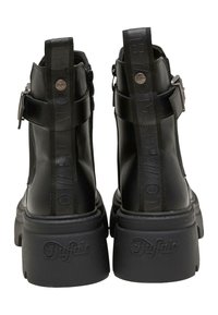Černé kožené kotníkové boty s mohutnou platformou, vybavené bočním zipem, akcentem přezky a embosovaným logem na bocích.