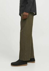 Pantalones de algodón verde oliva con corte recto, con una textura suave y bolsillos laterales, combinados con zapatos de ante negros.