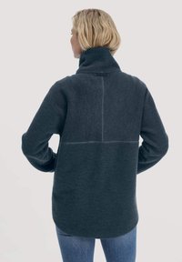 Pullover in pile grigio scuro con colletto alto, caratterizzato da un design senza cuciture e un sottile dettaglio di cucitura a contrasto lungo la schiena.