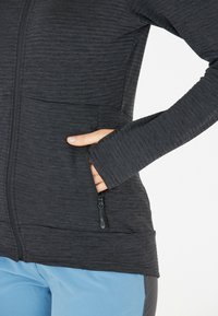 Donkergrijze ritsjack met een gestructureerde stof, twee zijzakken en lange mouwen. Heeft een slim-fit ontwerp en een soepele ritssluiting.