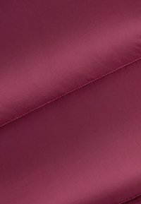 Głęboki burgundowy materiał o gładkiej, lekko błyszczącej teksturze; charakteryzuje się starannym przeszyciem wzdłuż krawędzi; płaski, bezszwowy design.