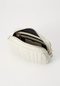 Witte, gequiltte leren tas met een zilveren rits. Heeft een ruime hoofdcompartiment en een zwarte binnenkant met een insteekvak.