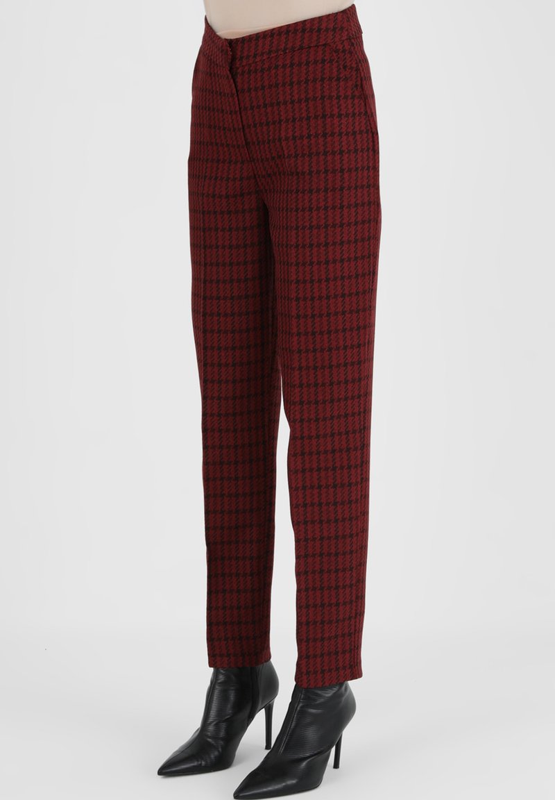 Rood en zwart houndstooth-gepatenteerde broek met een rechte pasvorm, voorzien van een rits en zijzakken, in combinatie met zwarte puntige enkellaarsjes.