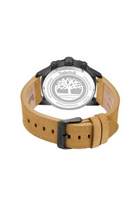 Rudas odinis laikrodžio dirželis su perforacijomis, pritvirtintas prie juodos metalinės korpuso, ant nerūdijančio plieno nugarėlės esantis baltas Timberland logotipas.