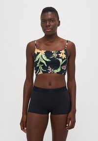 Schwarz gemustertes Cropped-Top mit Blumenmuster und dünnen Trägern, kombiniert mit hochgeschnittenen schwarzen Shorts mit einem elastischen, markierten Bund.