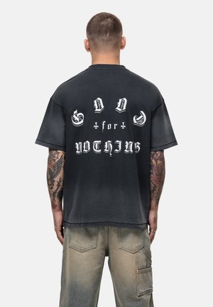 Black oversized t-shirt featuring bold white text on the back reading "GOD for NOTHING," short sleeves, and a soft, faded texture.