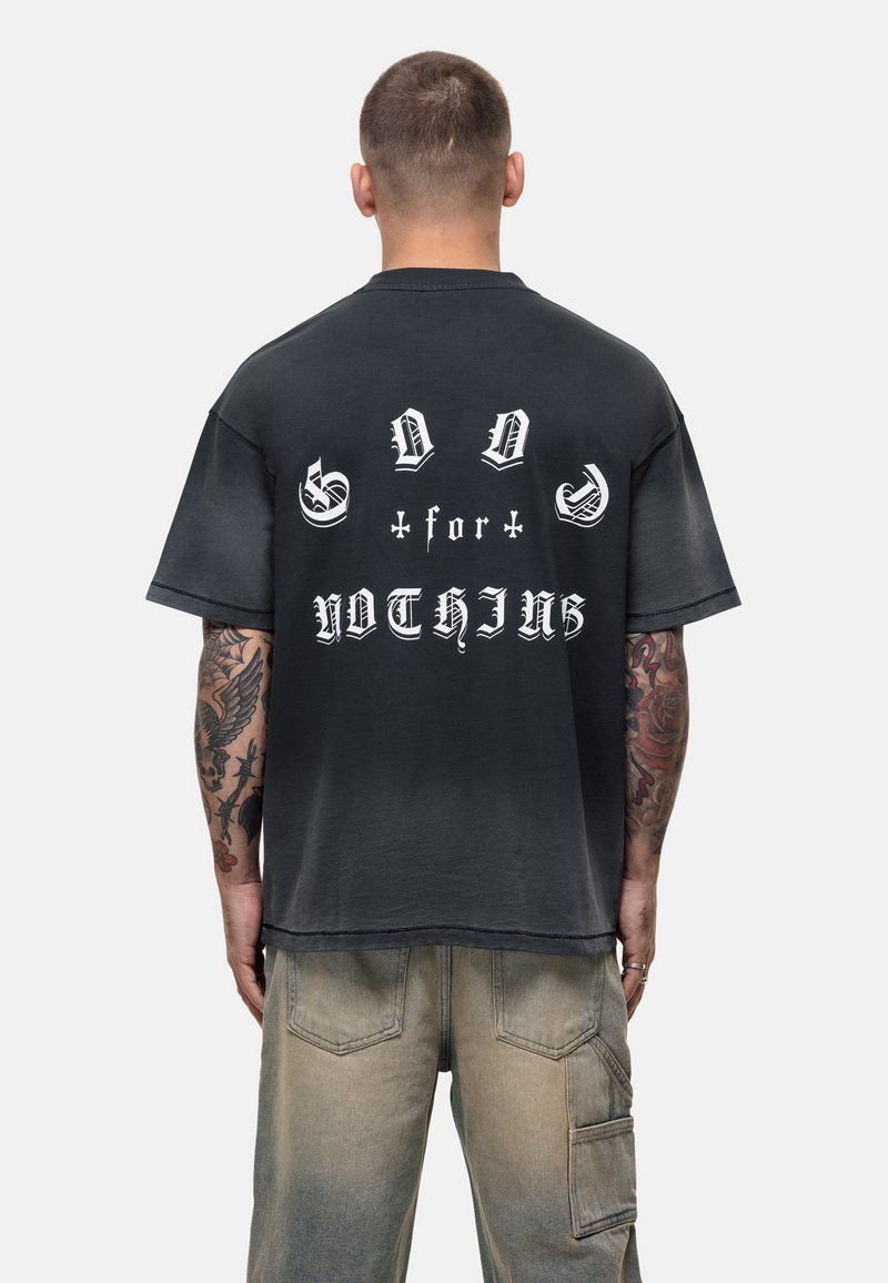 T-shirt noir oversize avec un grand texte blanc au dos indiquant "GOD for NOTHING", manches courtes et une texture douce et vieillie.