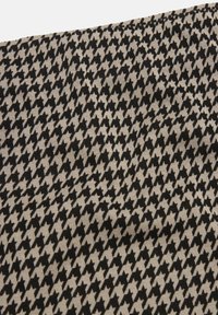 Mustavalkoinen houndstooth-kuvioinen kangas, jossa on sileä pinta ja vaihteleva geometrinen muotoilu koko ajan.