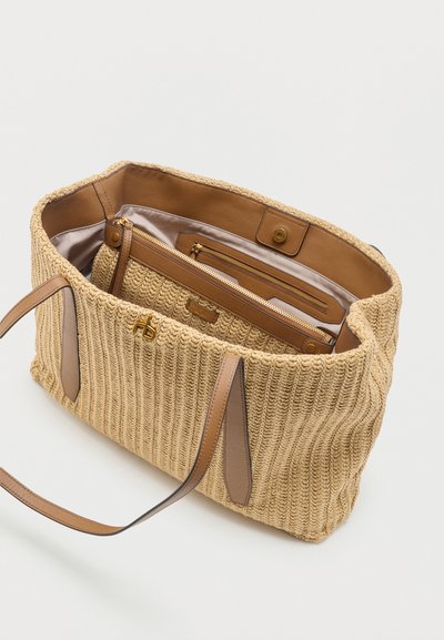 Μπεζ υφασμάτινη τσάντα ώμου με καφέ δερμάτινες λαβές, ανοιχτό πάνω μέρος που αποκαλύπτει εσωτερική φόδρα σε τόνο ταμπά και εσωτερικό φερμουάρ με χρυσό φερμουάρ.