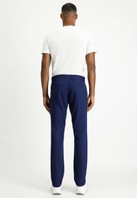 Pantaloni blu navy con design a gamba dritta, realizzati in un tessuto liscio. Presentano tasche posteriori e una vita aderente.