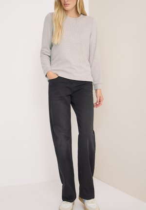 Sweatshirt léger gris clair à col rond avec des manches longues, associé à un pantalon droit noir et des baskets blanches. Texture lisse, coupe décontractée.