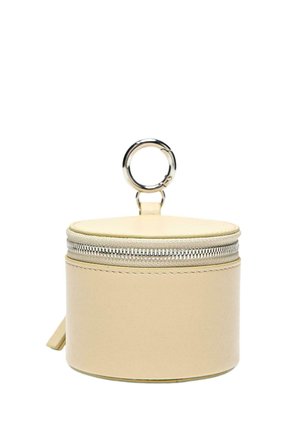 Piccola custodia rotonda beige in pelle con cerniera e portachiavi in metallo argentato attaccato sulla parte superiore, isolata su sfondo bianco.