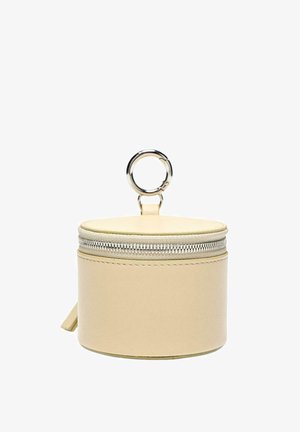 Piccola custodia rotonda beige in pelle con cerniera e portachiavi in metallo argentato attaccato sulla parte superiore, isolata su sfondo bianco.