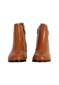 Bottines en cuir marron au design épuré, avec un petit talon carré et des zips latéraux pour faciliter l'enfilage. Texture lisse et forme sculptée.