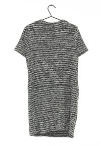 Šedé a černé krátké šaty s texturovaným pleteným vzorem. Tkanina se jeví jako měkká a ležérní, visí z černého háčku.